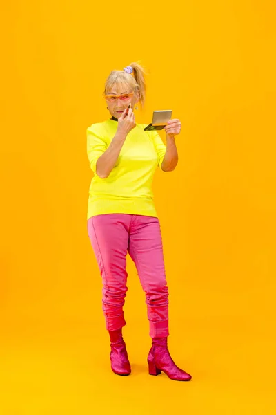 Senior woman in ultra trendy attire isolated on bright orange background — Stock Photo, Image