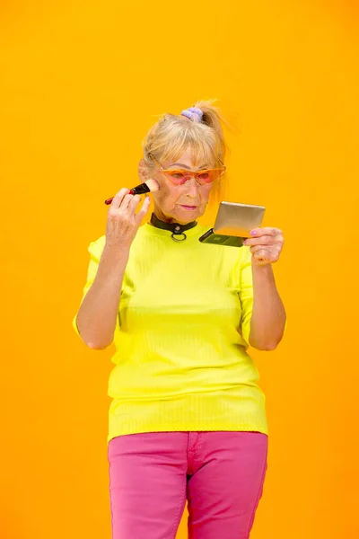 Senior vrouw in ultra trendy kleding geïsoleerd op fel oranje achtergrond — Stockfoto