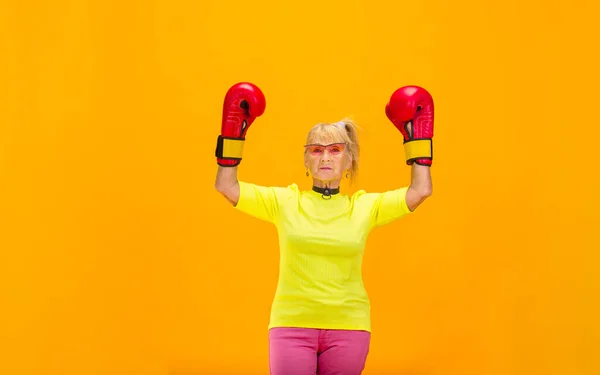 Seniorin in ultratrendiger Kleidung isoliert auf leuchtend orangefarbenem Hintergrund — Stockfoto