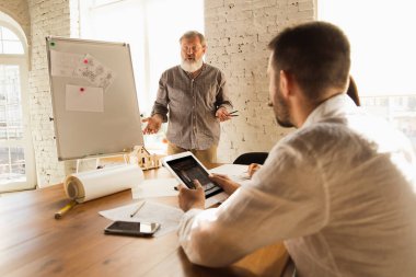 Erkek mimar-mühendis, genç aile için müstakbel ev projesini sunar..