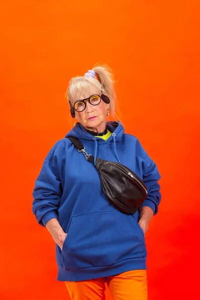 Mujer mayor en atuendo ultra moderno aislado sobre fondo naranja brillante — Foto de Stock