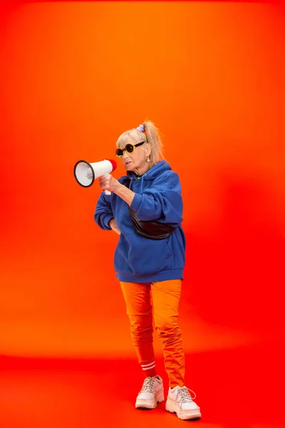 Senior γυναίκα σε ultra trendy ενδυμασία απομονώνονται σε φωτεινό πορτοκαλί φόντο — Φωτογραφία Αρχείου