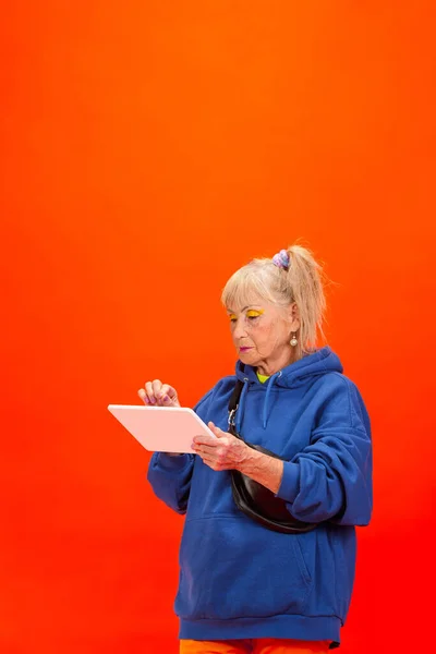 Idős nő ultra trendi öltözékben elszigetelt világos narancs háttér — Stock Fotó