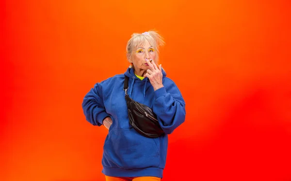 화려 한 의상을 입고 밝은 오렌지 색 배경에 고립 된 나이든 여자 — 스톡 사진