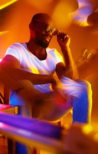Cinematografisch portret van knappe jongeman in neon verlichte kamer, stijlvolle muzikant — Stockfoto