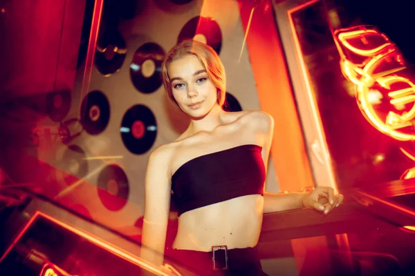 Neon ışıklı odada yakışıklı genç bir kadının sinematik portresi, şık bir müzisyen.