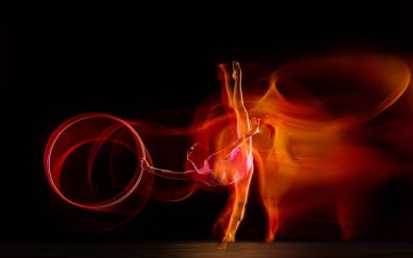 Genç esnek bayan jimnastikçi, siyah stüdyo arka planında karışık ışıkta izole edilmiş.,