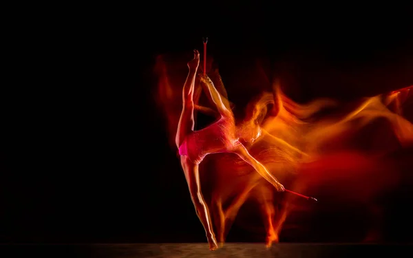 Jeune gymnaste féminine flexible isolée sur fond de studio noir en lumière mixte, — Photo