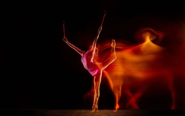 Jeune gymnaste féminine flexible isolée sur fond de studio noir en lumière mixte, — Photo