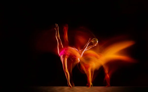 Junge flexible Turnerin isoliert auf schwarzem Studiohintergrund in gemischtem Licht, — Stockfoto