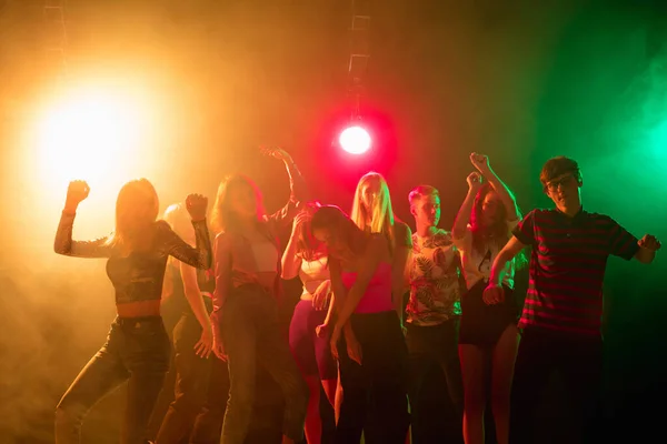 Eine Menschenmenge in Silhouette hebt die Hände auf der Tanzfläche vor Neonlicht-Hintergrund — Stockfoto