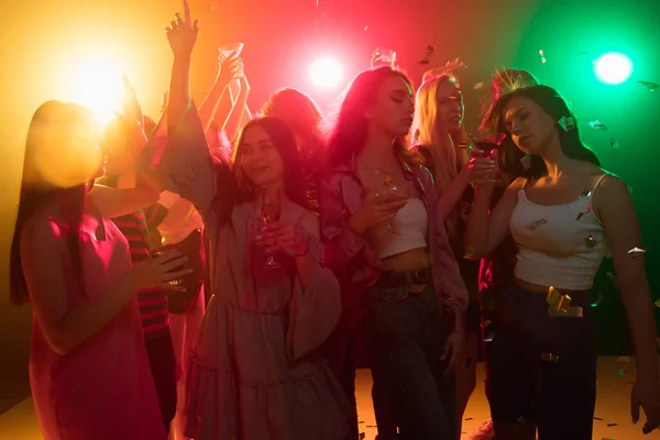 A crowd of people in silhouette raises their hands on dancefloor on neon light background — Stock Photo, Image