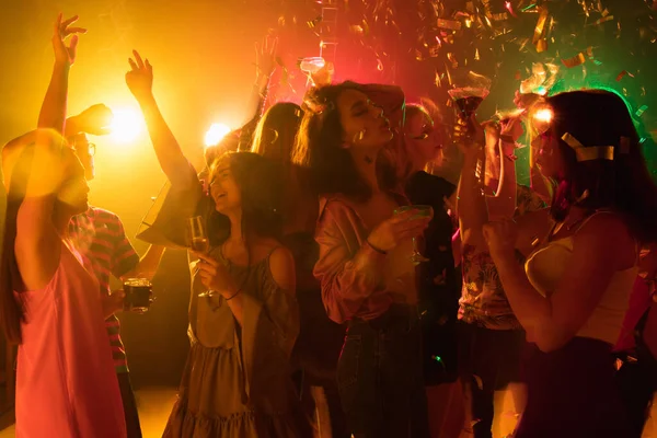 Натовп людей в силуеті піднімає руки на танцмайданчику на неоновому світлому фоні — стокове фото