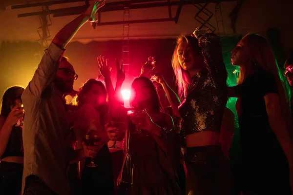 A tömeg a sziluett felemeli a kezét a táncparketten neon fény háttér — Stock Fotó