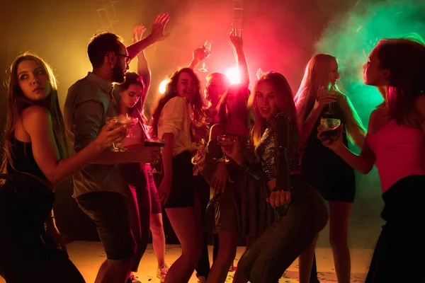 Eine Menschenmenge in Silhouette hebt die Hände auf der Tanzfläche vor Neonlicht-Hintergrund — Stockfoto