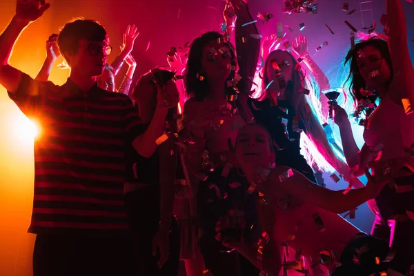 Dav lidí v siluetě zvedne ruce na tanečním parketu na neonovém světlém pozadí — Stock fotografie