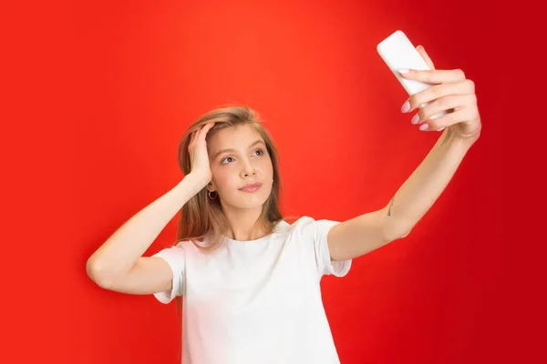 Portrét mladé bělošky s jasnými emocemi na jasně červeném pozadí studia — Stock fotografie