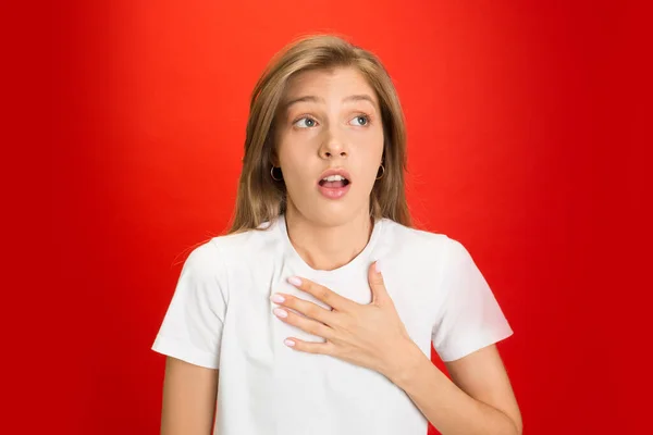 Retrato de mujer joven caucásica con emociones brillantes sobre fondo de estudio de color rojo brillante —  Fotos de Stock