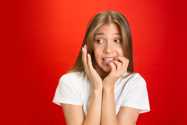 Porträt einer jungen kaukasischen Frau mit hellen Emotionen auf leuchtend rotem Studiohintergrund — Stockfoto