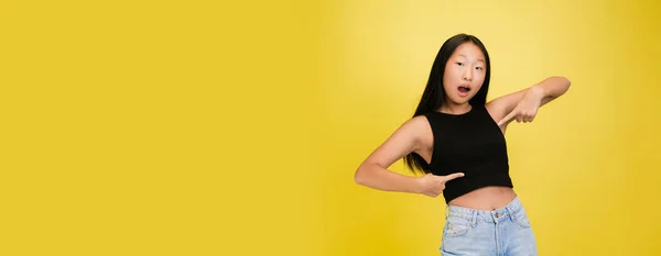 Портрет молодой азиатской девушки на фоне жёлтой студии — стоковое фото