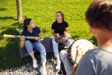 Tekerlekli sandalyede arkadaşlarıyla dışarıda enstrümantal müzik çalarak vakit geçiren mutlu engelli adam.