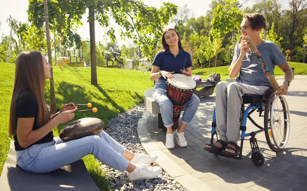 Gelukkig gehandicapte man in een rolstoel tijd doorbrengen met vrienden spelen live instrumentale muziek buiten — Stockfoto