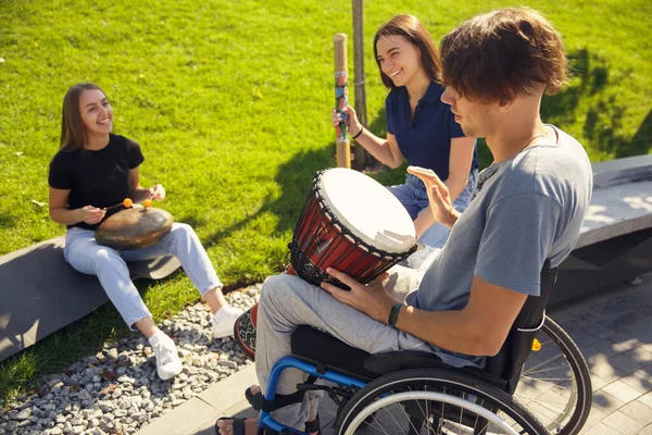 Gelukkig gehandicapte man in een rolstoel tijd doorbrengen met vrienden spelen live instrumentale muziek buiten — Stockfoto