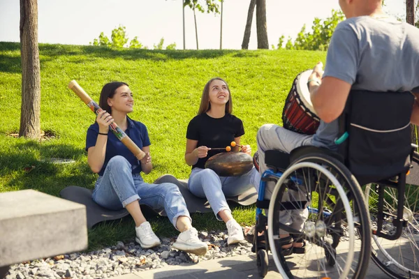 Gelukkig gehandicapte man in een rolstoel tijd doorbrengen met vrienden spelen live instrumentale muziek buiten — Stockfoto