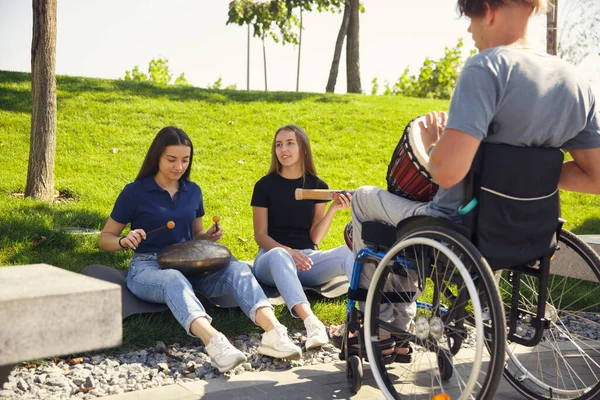 Gelukkig gehandicapte man in een rolstoel tijd doorbrengen met vrienden spelen live instrumentale muziek buiten — Stockfoto