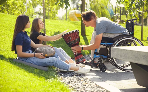 Gelukkig gehandicapte man in een rolstoel tijd doorbrengen met vrienden spelen live instrumentale muziek buiten — Stockfoto