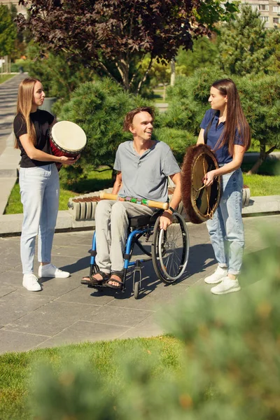 Gelukkig gehandicapte man in een rolstoel tijd doorbrengen met vrienden spelen live instrumentale muziek buiten — Stockfoto