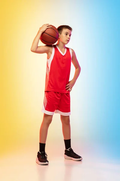 Full length portrait of a young basketball player with ball on gradient background — Stock Photo, Image