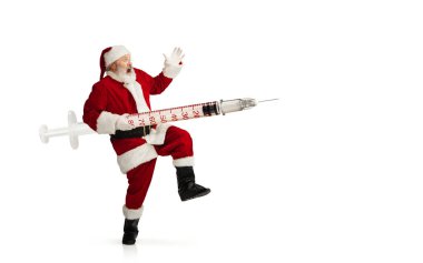 Noel Baba COVID 'e karşı büyük bir aşı tutuyor. Beyaz arka planda izole edilmiş bir Noel hediyesi gibi.