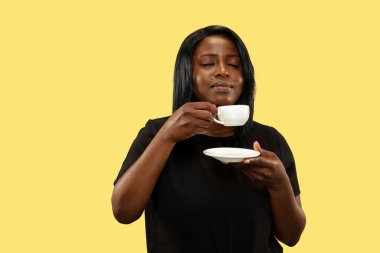 Sarı stüdyo arka planında izole edilmiş genç Afrikalı kadın, yüz ifadesi