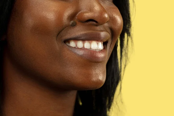 Jeune femme africaine isolée sur fond de studio jaune, expression faciale — Photo