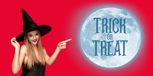 Young woman in hat as a witch on scary red background