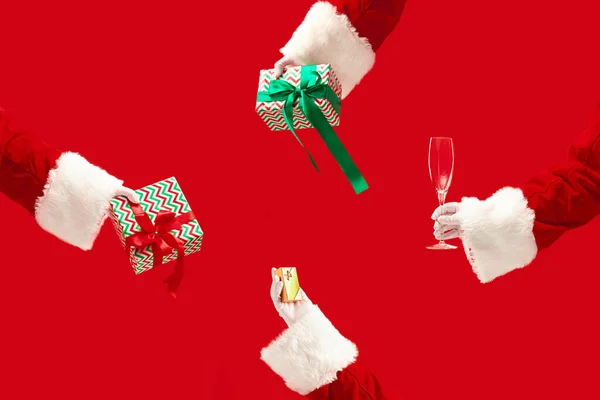 As mãos de Papai Noel segurando um presente em fundo vermelho com copyspace. Ano Novo, Natal, inverno, feriado, celebração, conceito de presente — Fotografia de Stock