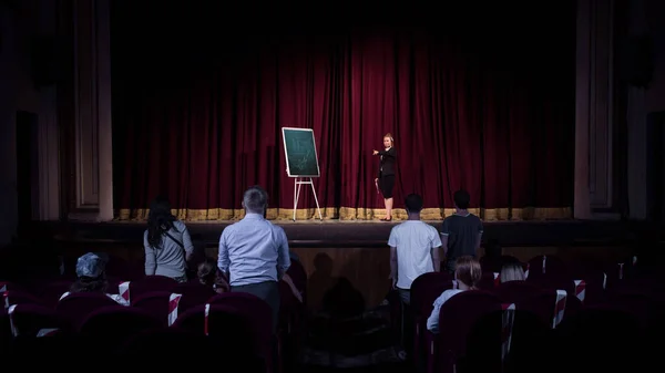 Female caucasian speaker giving presentation in hall at university or business centre workshop