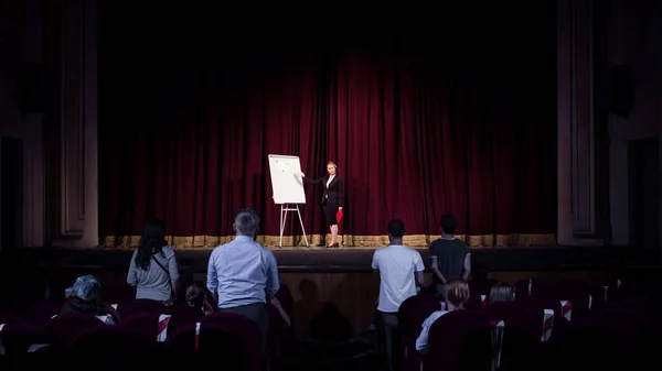 Female caucasian speaker giving presentation in hall at university or business centre workshop