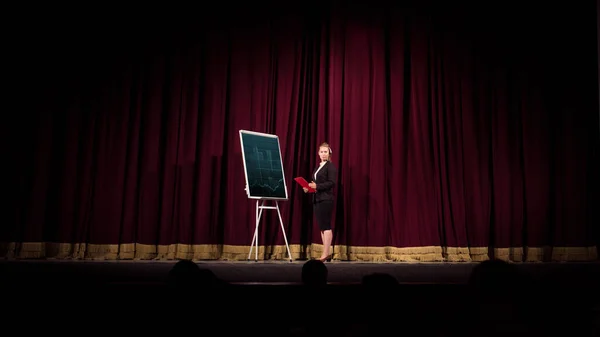 Female caucasian speaker giving presentation in hall at university or business centre workshop