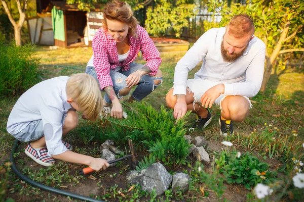 Glückliche Familie bei der Pflanzenpflege im Garten im Freien. Liebe, Familie, Lebensstil, Erntekonzept. — Stockfoto