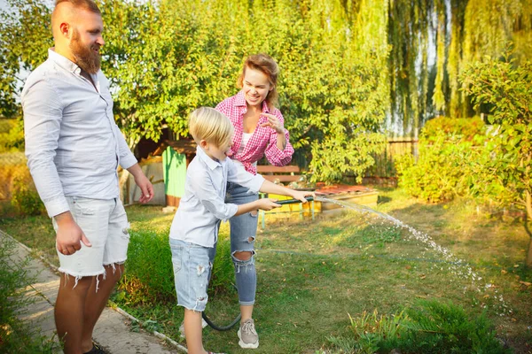 Glückliche Familie beim Pflanzen gießen im Garten im Freien. Liebe, Familie, Lebensstil, Erntekonzept. — Stockfoto