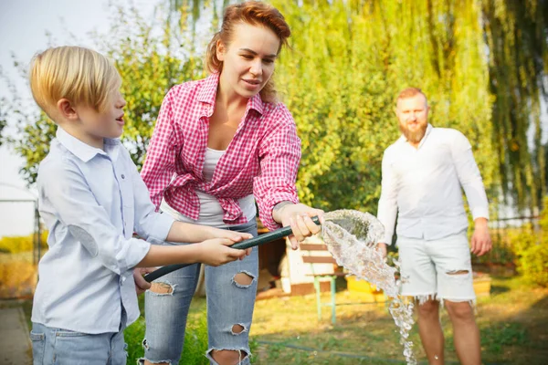 Happy family during watering plants in a garden outdoors. Love, family, lifestyle, harvest concept. — Stock Photo, Image