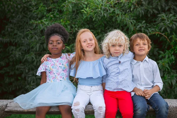 Interracial group of kids, girls and boys playing together at the park in summer day