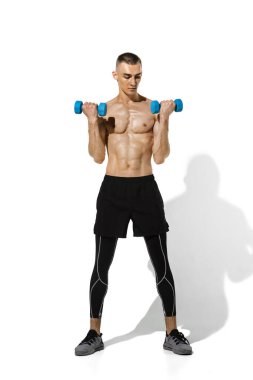 Beyaz stüdyo arka planında gölgelerle pratik yapan genç ve güzel bir sporcu.