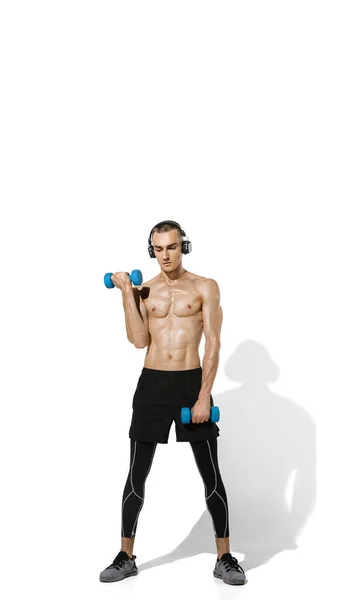 Hermoso joven atleta masculino practicando en fondo blanco estudio con sombras —  Fotos de Stock