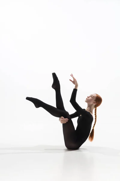 Joven y elegante bailarina de ballet en estilo minimalista negro aislado sobre fondo de estudio blanco — Foto de Stock