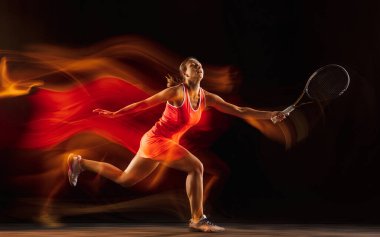 Profesyonel bayan tenisçi, siyah stüdyo arka planında karışık ışıkta izole edilmiş.