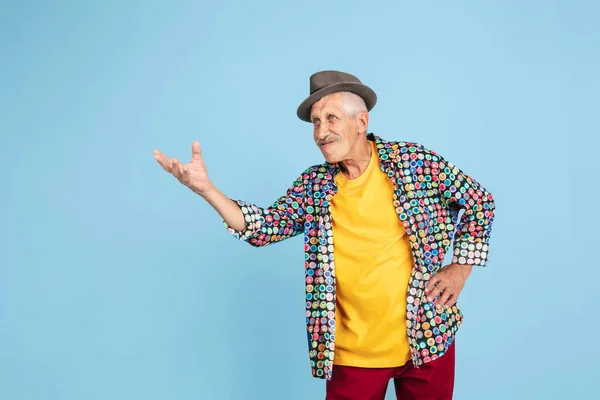 Homem hipster sênior em chapéu elegante isolado em fundo azul. Conceito de tecnologia e estilo de vida idoso alegre — Fotografia de Stock