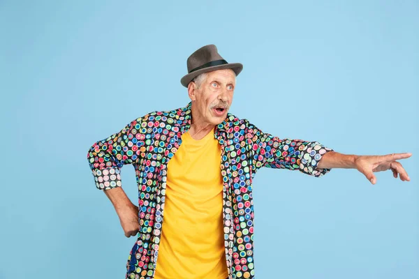 Starší hipster muž ve stylovém klobouku izolované na modrém pozadí. Technický a radostný životní styl seniorů — Stock fotografie